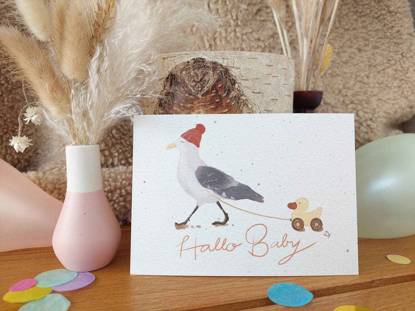 Postkarte zur Geburt - Möwe mit roter Mütze spaziert mit einer kleinen gelben Holzente. Spruch: Hallo Baby