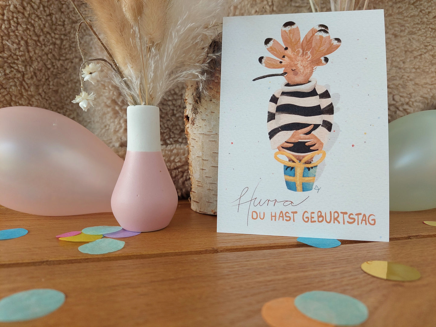 Karte zum Geburtstag mit Spruch Hurra du hast Geburtstag. Ein lustiger Wiedehopf, Vogel mit vielen Federn auf dem Kopf, steht stolz auf einem kleinen blauen Geschenk.