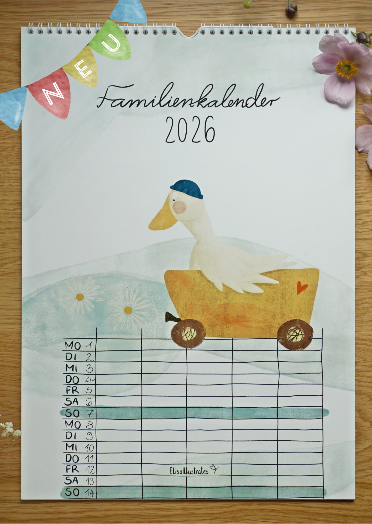 Familienkalender 2026 liegt mit Blumen auf einem Holztisch. Mit handgezeichneten Aquarell-Kreide-Motiven, fünf Spalten und allen gesetzlichen Feiertagen in Deutschland. Auf dem Deckblatt ist eine Gans mit Mütze in einem Wagen zu sehen.