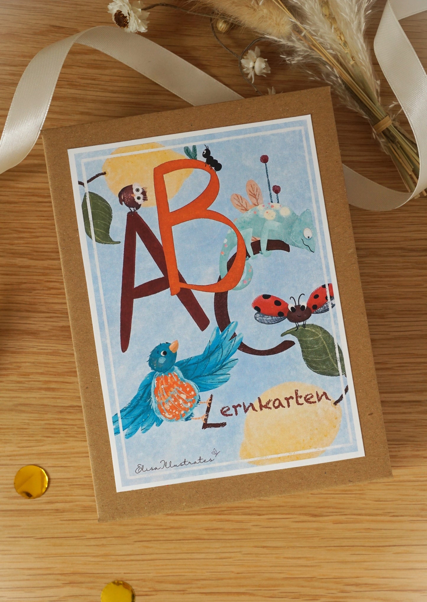 ABC Lernkarten Box mit schönem Buchstabencover und Illustrationen auf einem Holztisch