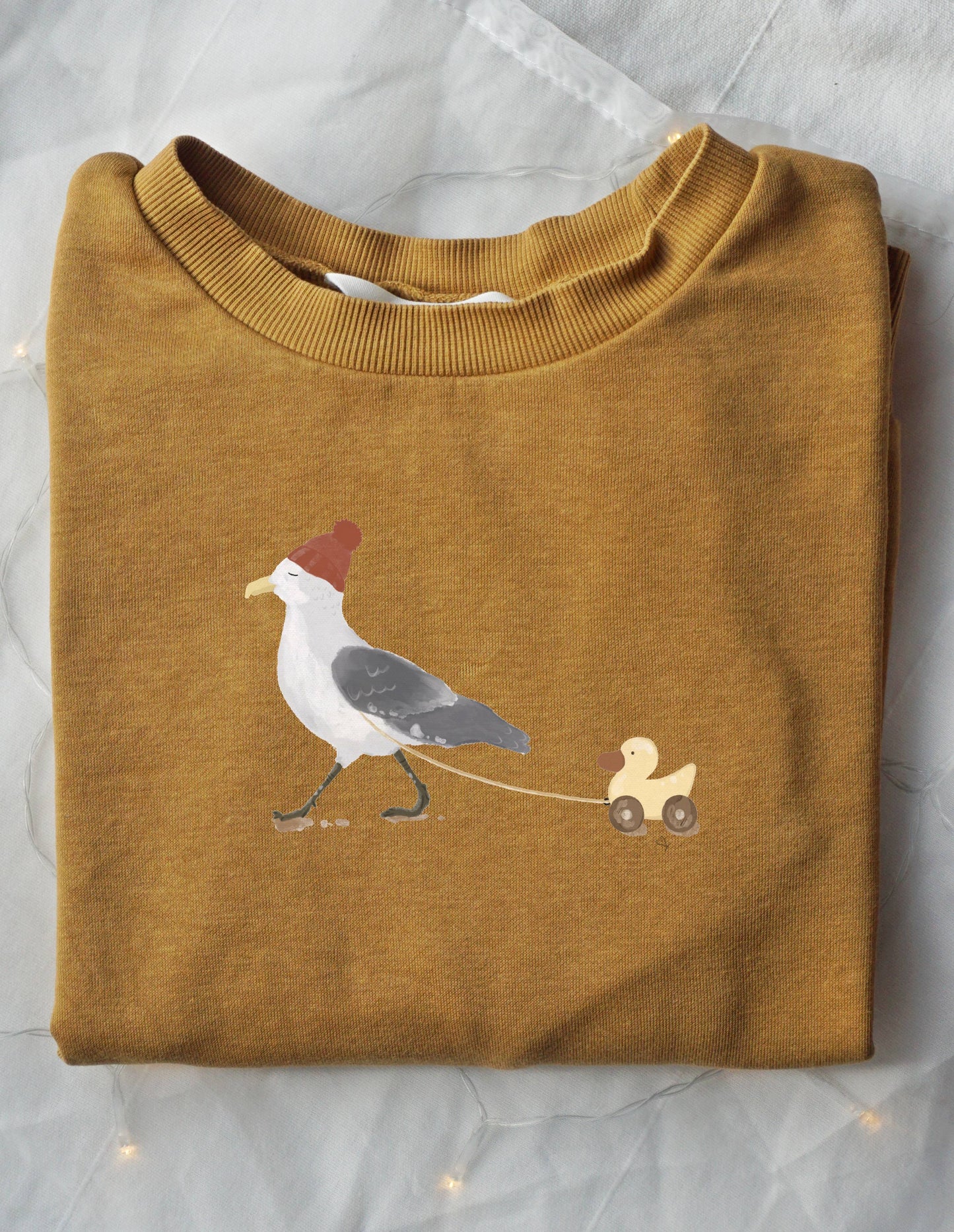 Bügelbild von einer Möwe, die eine Spielzeigente hinter sich herzieht zum Aufbügeln auf deine Lieblingskleidungsstücke für Kinder und Erwachsene. Handgezeichnete Illustration von einer Möwe