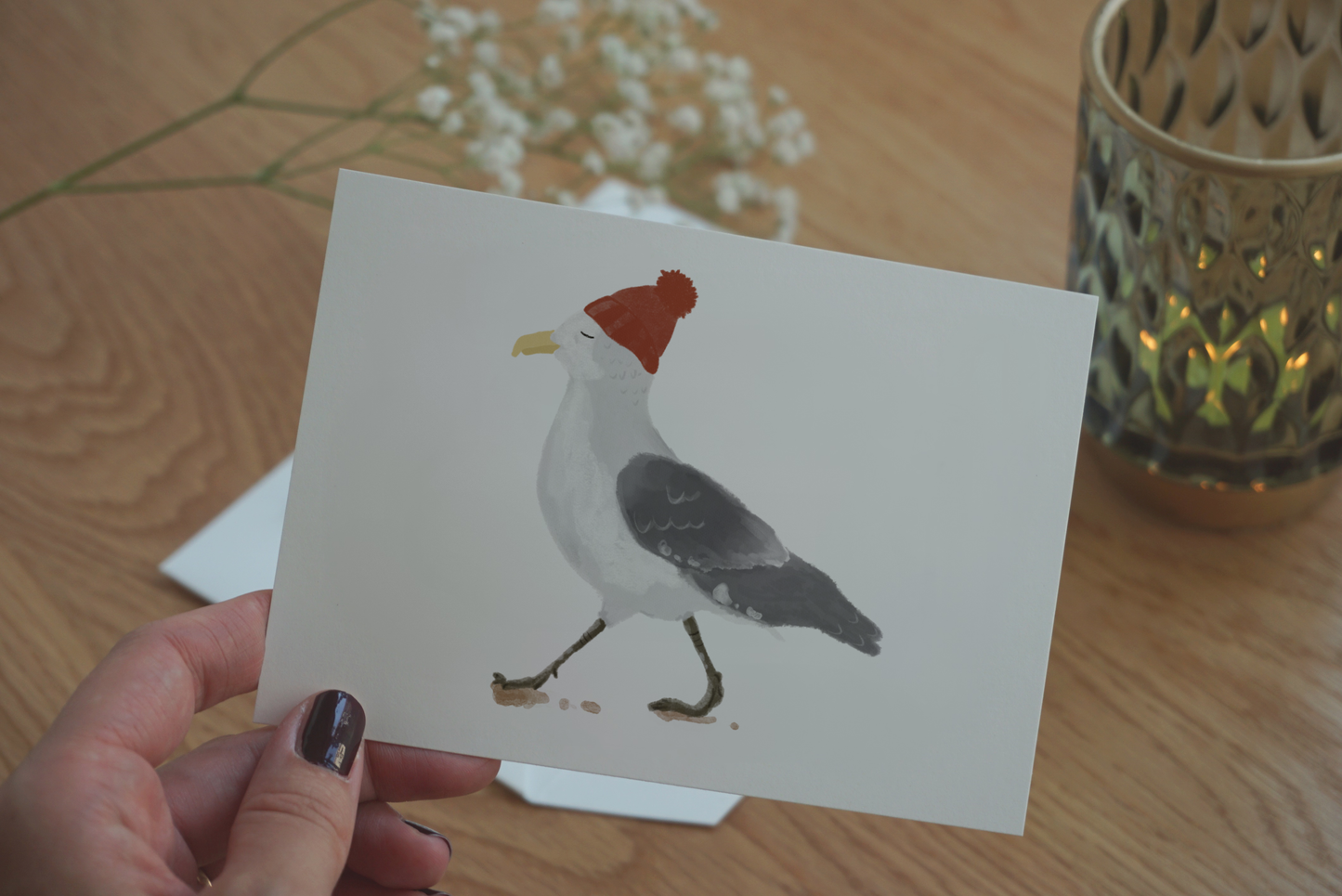 Das Bild Möwe ist eine handgemalte Illustration. Man sieht die schöne, detaillierte Struktur des Motives. Eine entspannt blickende Möwe mit roter Mütze.