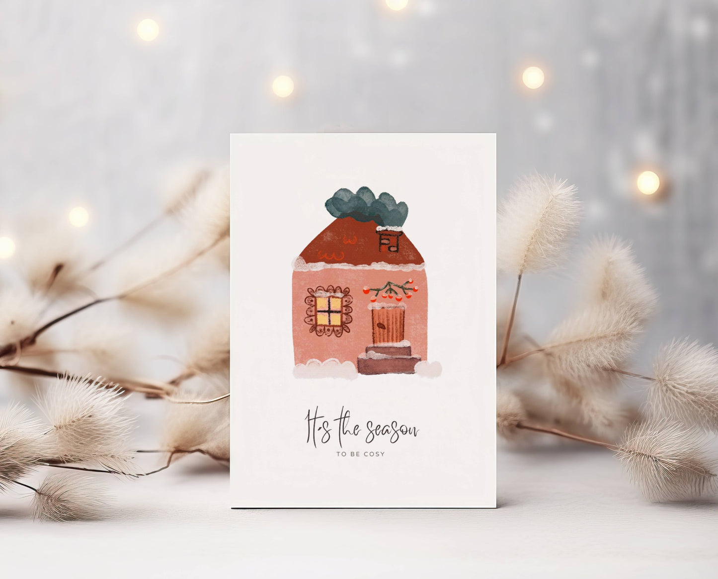 Grüße und Wünsche zu Weihnachten und in der Winterzeit auf dieser süßen selbstgemalten Karte. Hübsch, gemütlich verziertes Haus mit Beeren, Schnee und warmem Licht. Darunter der Spruch: It´s the season to be cosy