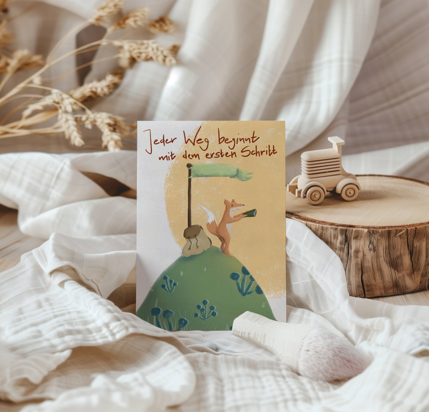 Die Postkarte Mutiger Fuchs mit Spruch - Jeder Weg beginnt mit dem ersten Schritt - steht angelehnt an einem Stück Birke in natürlichem Ambiente mit Holzspielzeug. Karte zum Schulstart