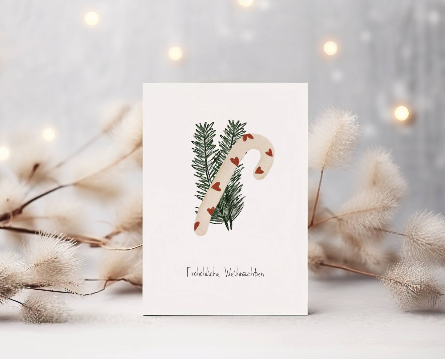 Grüße und Wünsche zu Weihnachten und in der Winterzeit auf dieser süßen selbstgemalten Karte. Eine Zuckerstange mit roten Herzen vor zwei Tannezweigen. Darunter der Spruch: Fröhöliche Weihnachten