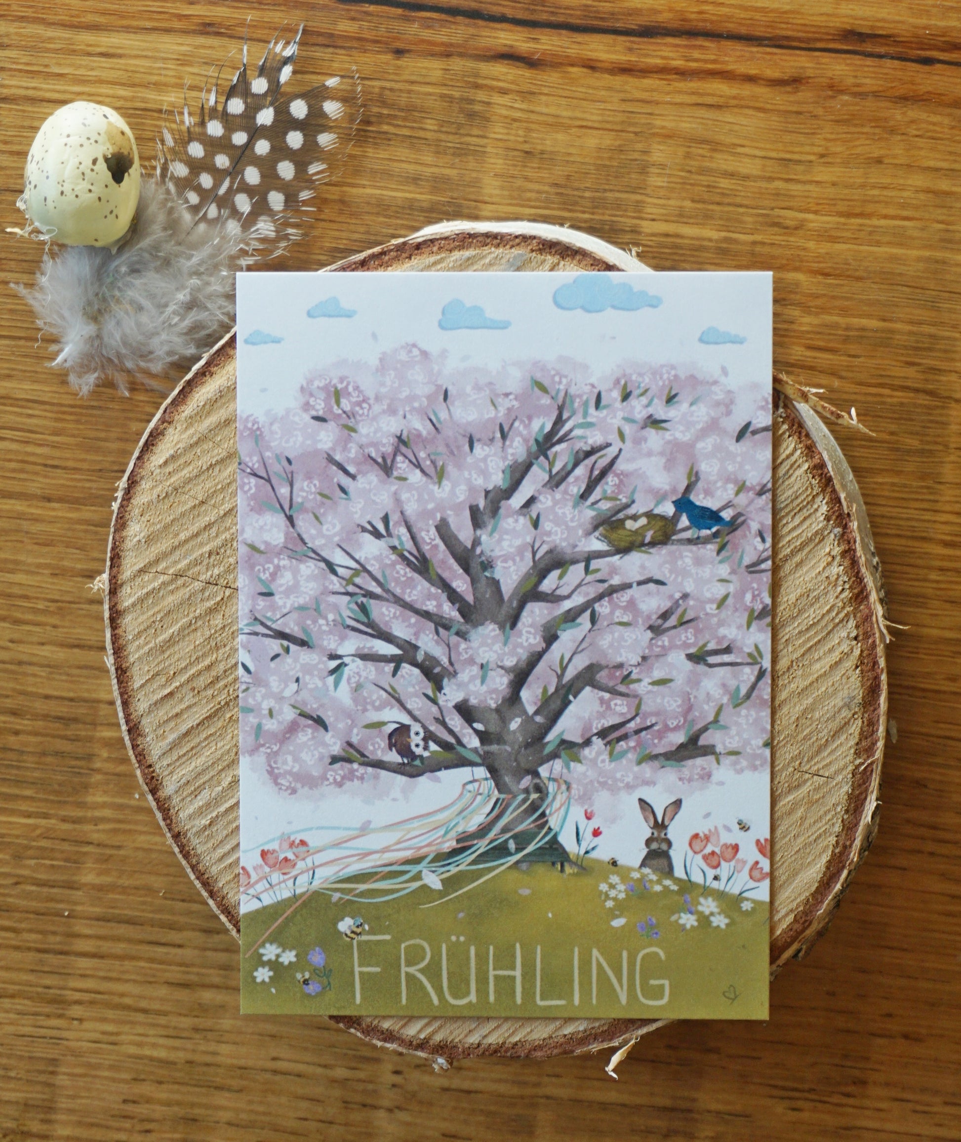 Bild Frühling Baum mit rosa Blüten, Vogelnest mit Eiern und blauer Vogelmama, lustige Tiere, Frühblüher auf der Wiese, Maikranz mit bunten Bändern wehen im Wind vom Baum